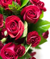 Alternative image 4 for A striking arrangement featuring red roses, red mini carnations, and salal, elegantly presented in a red gathering vase. This bold and vibrant display is perfect for adding a touch of elegance and passion to any occasion.