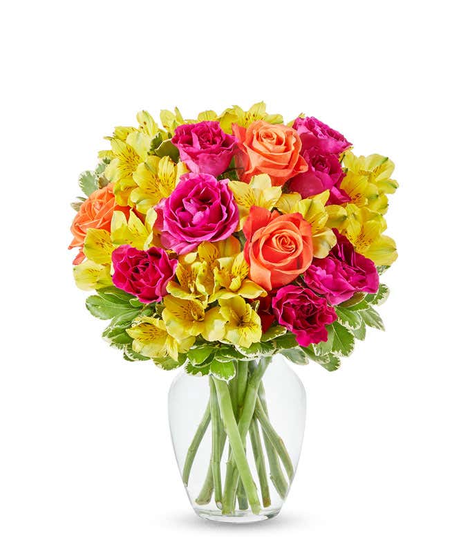 Orange roses, hot pink roses and yellow alstroemeria in glass vase