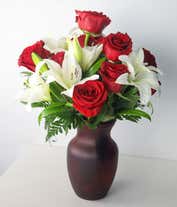 Alternative image 1 for A floral arrangement featuring red roses and white lilies in a red cylinder vase.
