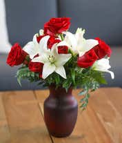 Alternative image 3 for A floral arrangement featuring red roses and white lilies in a red cylinder vase.