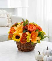 Alternative image 3 for A vibrant floral arrangement featuring yellow Asiatic lilies, deluxe size orange roses, regular size orange carnations, yellow button poms, bronze cushion poms, red hypericum, and solidago, all beautifully presented in a basket.