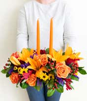 Alternative image 2 for Fall centerpiece with orange candles, orange lilies, roses, yellow poms, purple statice, and red hypericum berries.