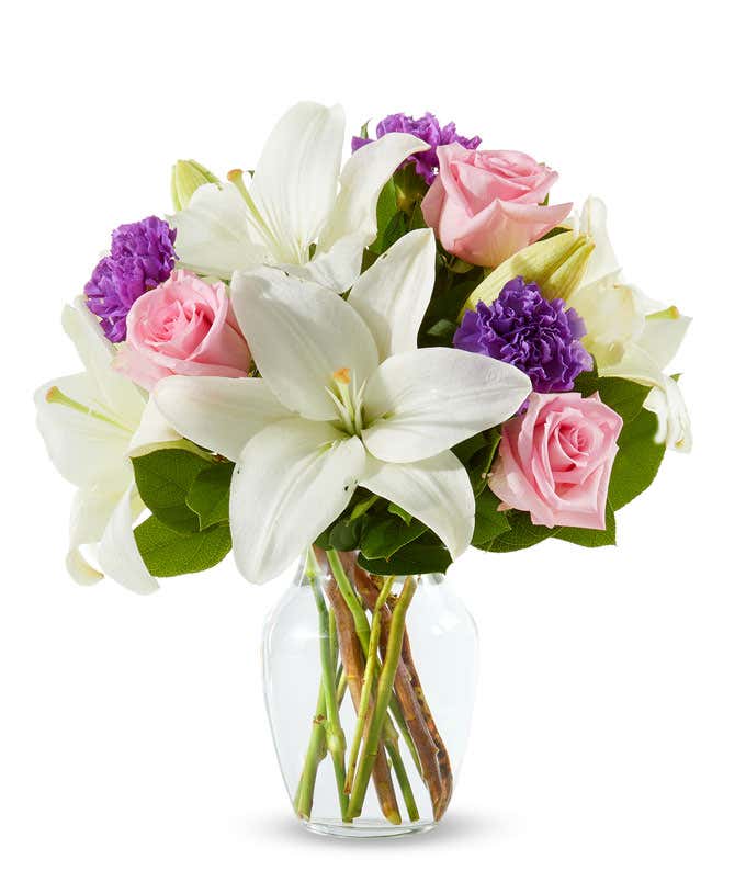 pink roses, purple carnations and white lilies in a clear Vase