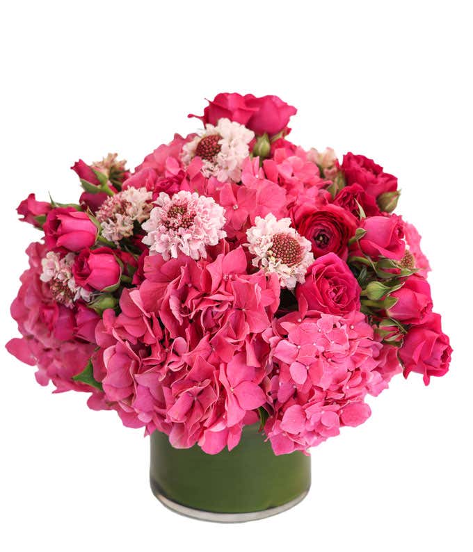 Hot pink and light pink flowers arranged into a leaf-lined vase.