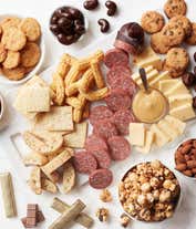 Alternative image 1 for Woven gift basket with gourmet snacks: butter toffee pretzels, salted caramel popcorn, biscotti, toasted crackers, dark chocolate cashews, chocolate chip cookies, honeycomb chocolates, truffles, cheddar cheese, beef sausage, almonds, cheese straws, and a 