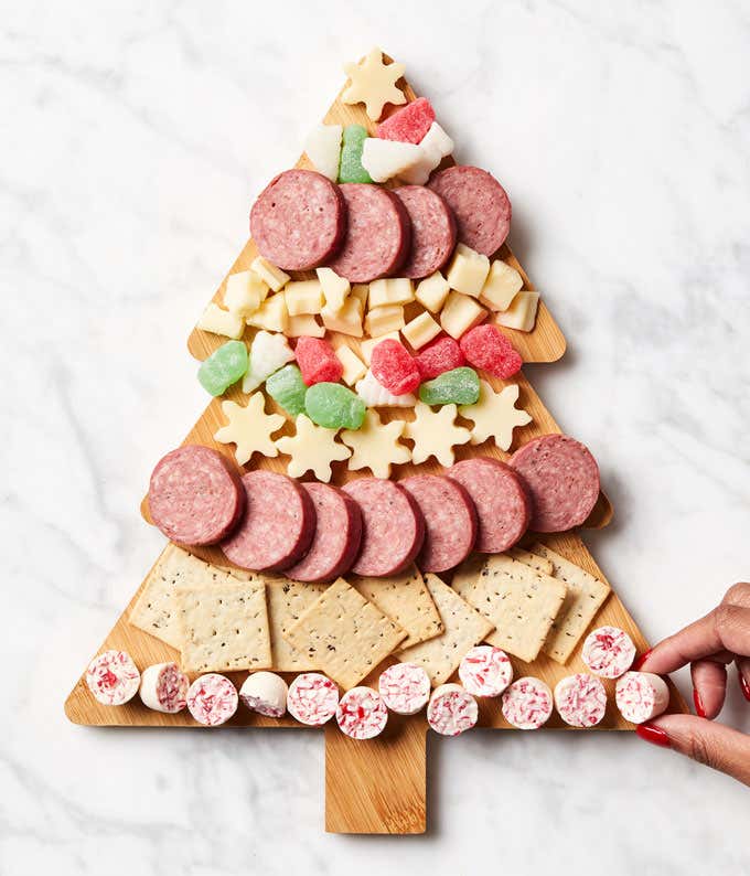 A kit gift box featuring an image of a holiday-themed charcuterie board arranged in the shape of a Christmas tree. The kit includes an assortment of meats, cheeses, and festive candies, with easy instructions for assembly.