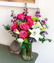 Alternative image 1 for Dark pink roses, white Asiatic lilies, lavender stock, green button spray chrysanthemums, lavender sinuata statice, sword fern, huckleberry in a cylinder vase.