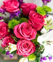 Alternative image 3 for Dark pink roses, white Asiatic lilies, lavender stock, green button spray chrysanthemums, lavender sinuata statice, sword fern, huckleberry in a cylinder vase.