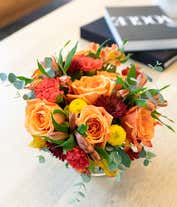 Alternative image 3 for A vibrant fall-themed floral arrangement featuring orange fall roses, orange alstroemeria, yellow button mums, burgundy cushion mums, and orange carnations, all elegantly displayed in a cylinder vase.