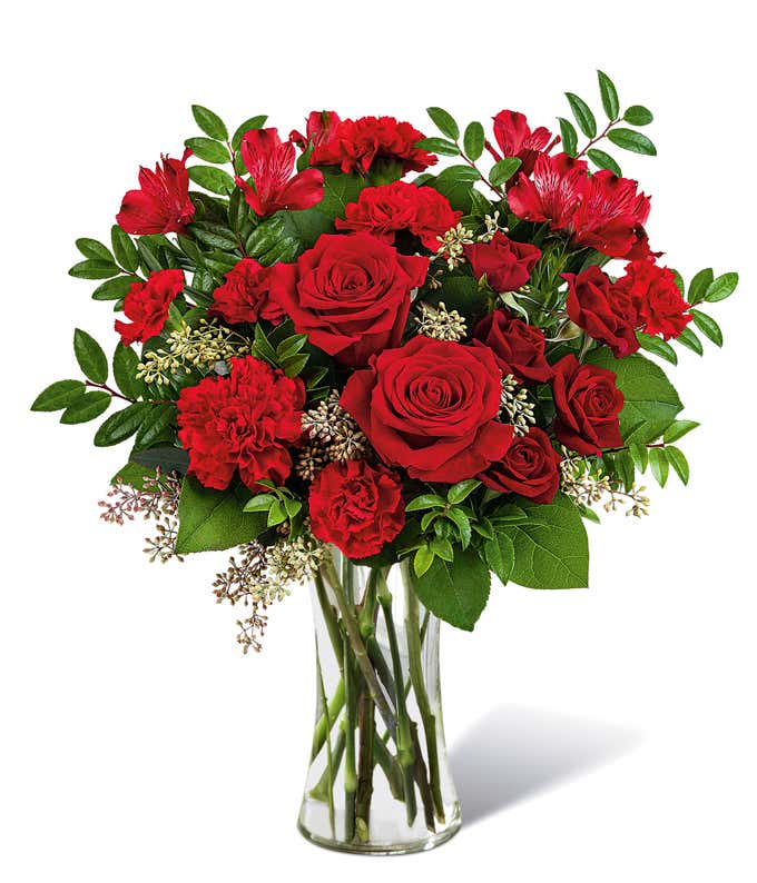 Full arrangement of red roses and carnations in a tall red mosaic vase,