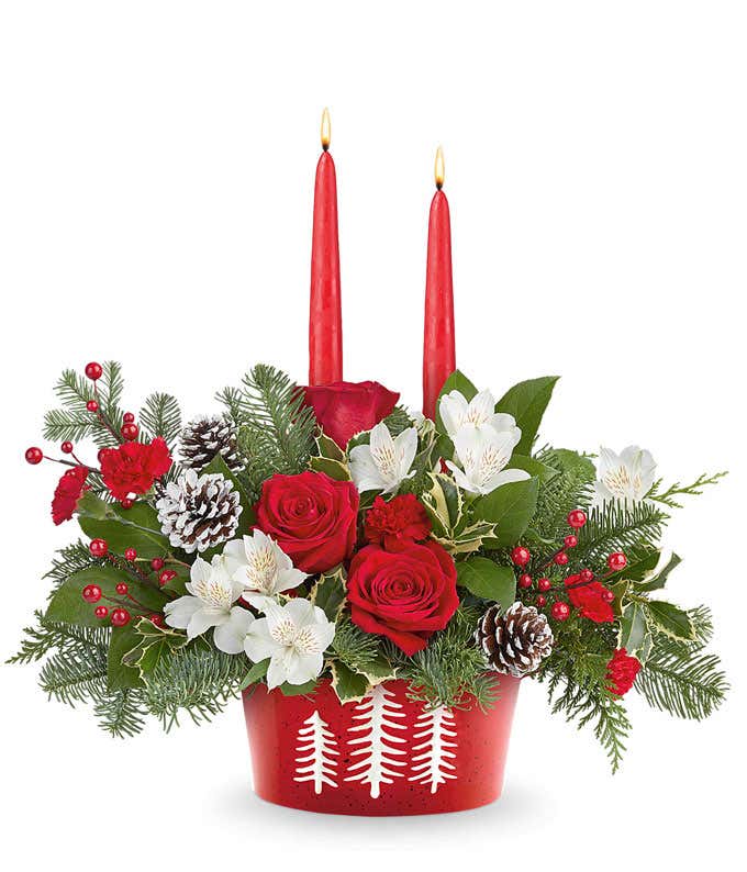 Holiday bouquet with red roses, white alstroemeria, and miniature red carnations in a polar bear mug with festive greenery and red-and-white striped ribbon.