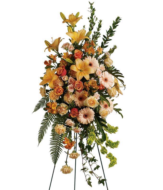 Standing Funeral Spray: Peach roses, orange roses, peach asiatic lilies, peach gerberas, orange alstroemeria, peach carnations, and floral greenery, symbolizing love and cherished memories.