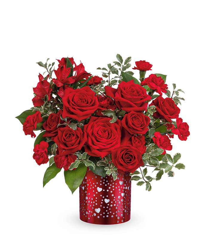 Valentine’s Day arrangement of classic red roses with lush greenery displayed in a red cylinder vase heart cutouts