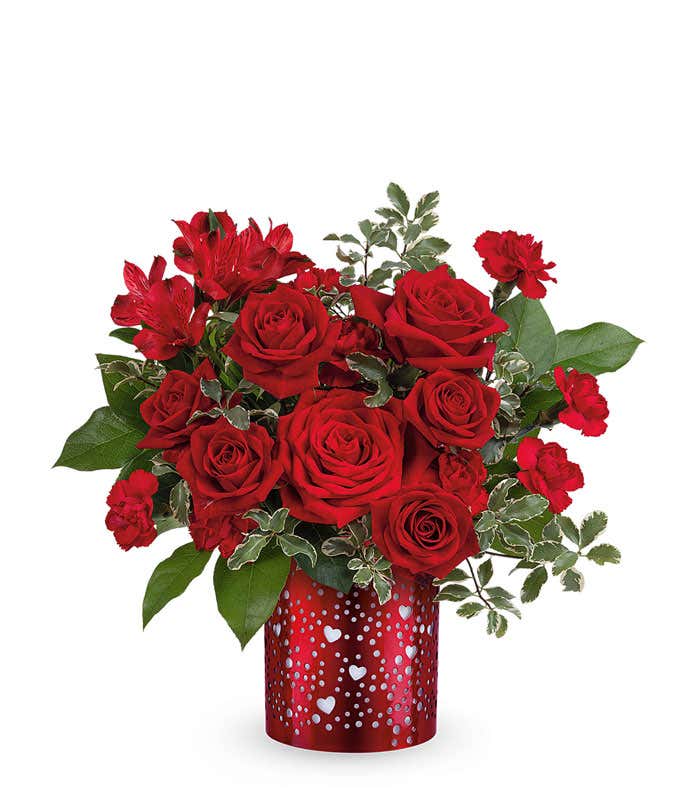 Valentine’s Day arrangement of classic red roses with lush greenery displayed in a red cylinder vase heart cutouts