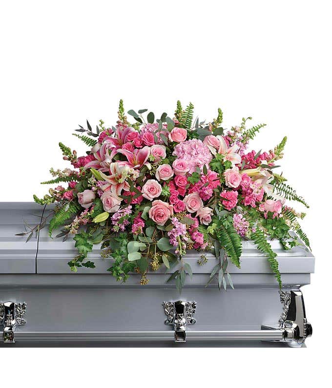 A pink floral casket spray with hydrangea, roses, stargazer lilies, carnations, snapdragon, and floral greens