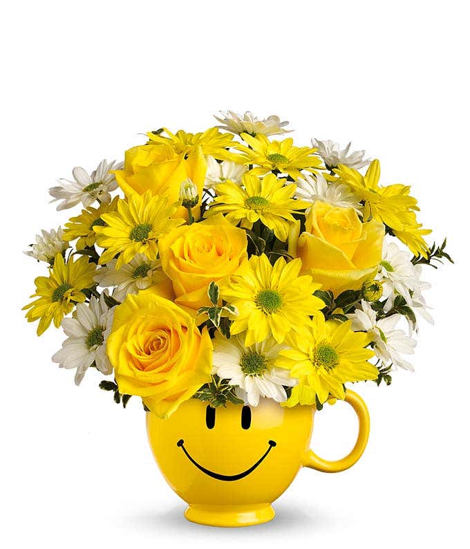 Yellow roses and bright daisies in a yellow smiley face mug