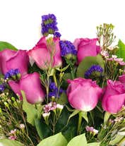 Alternative image 1 for A striking arrangement featuring purple roses, seasonal greens, elegantly presented in a square glass vase adorned with a purple ribbon. This beautiful combination offers a luxurious and sophisticated display, perfect for any special occasion.