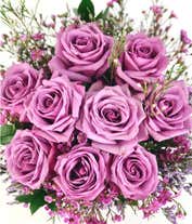 Alternative image 2 for A striking arrangement featuring purple roses, seasonal greens, elegantly presented in a square glass vase adorned with a purple ribbon. This beautiful combination offers a luxurious and sophisticated display, perfect for any special occasion.