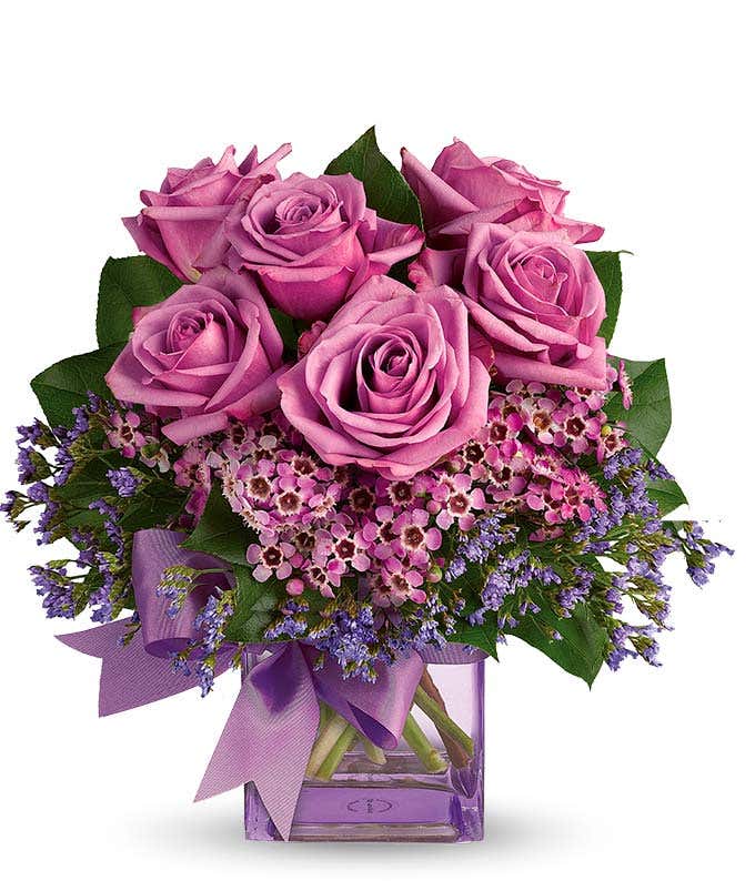 Purple roses in square glass vase