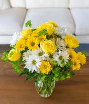 Alternative image 1 for A cheerful arrangement featuring white daisy spray chrysanthemums, yellow daisy spray chrysanthemums, and assorted greens, all elegantly presented in a clear vase. This bright and fresh display is perfect for adding a touch of sunshine to any space.