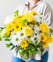 Alternative image 3 for A cheerful arrangement featuring white daisy spray chrysanthemums, yellow daisy spray chrysanthemums, and assorted greens, all elegantly presented in a clear vase. This bright and fresh display is perfect for adding a touch of sunshine to any space.