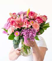 Alternative image 4 for Floral arrangement featuring pink roses, pink Asiatic lilies, pink carnations, pink Matsumoto asters, lavender cushion spray chrysanthemums, pink statice, dusty miller, lemon leaf, in a clear vase.