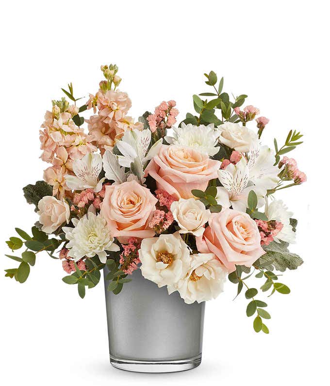 Elegant floral arrangement with soft pink roses, white roses, white chrysanthemums, pink stock, and white alstroemeria in a sleek silver vase, perfect gift for loved ones.