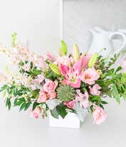 Alternative image 1 for A beautiful arrangement featuring pink spray roses, pink lilies, pink alstroemeria, pink carnations, pink lisianthus, pink larkspur, white statice, and an echeveria succulent, all presented in a keepsake vase. This vibrant pink display offers a charming a
