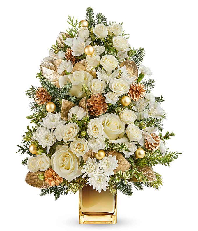 Holiday tree-shaped floral arrangement with white roses, carnations, chrysanthemums, gold pinecones, ornaments, and evergreens in a gold vase.