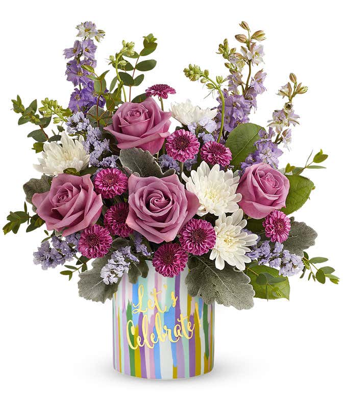 Lavender roses arranged with purple button chrysanthemums, lavender larkspur, lavender sinuata statice, and floral greens in a keepsake 