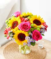 Alternative image 2 for Floral arrangement featuring sunflowers, red alstroemeria, pink roses (in deluxe and premium versions), purple monte casino, and green button poms in a mason jar vase, with a personalized card message.