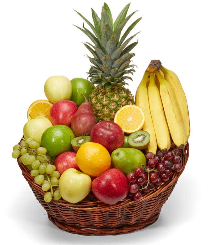 Wicker basket filled with a variety of fresh fruit including a pineapple, bananas, red and green apples, pears, oranges, kiwi, grapes, and a sliced orange.