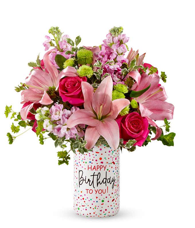 Pink lilies, roses, and gilly flowers, with fresh floral greens in a clear glass vase