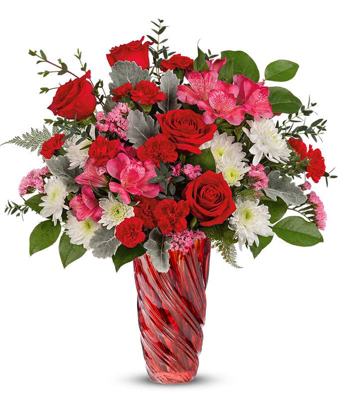 Flowers of red, pink, and white arranged into a tall red Swirled Vase