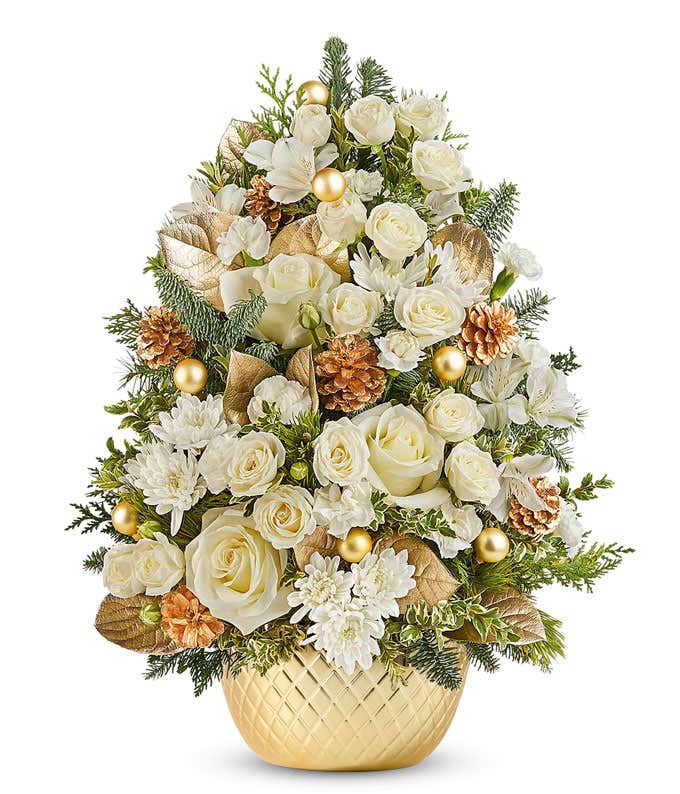 Mini Christmas Tree with White Roses, White Spray Roses, White Alstroemeria, White Mini Carnations, and festive seasonal greenery in a gold bowl