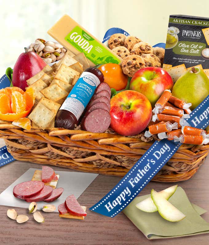 The image shows a woven basket filled with fresh fruits, cheese, sausage, crackers, and cookies, decorated with a blue ribbon that reads 'Happy Father's Day.' The colorful assortment creates a vibrant and appealing display.