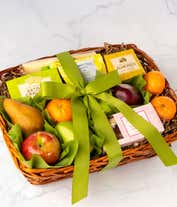 Alternative image 1 for A basket filled with fresh fruits, crackers, cheese crisps, almonds, honey mustard, and assorted caramels, adorned with a green ribbon. 