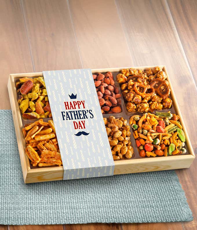 Wooden tray with six compartments filled with assorted snacks, including caramel popcorn with pretzels, almonds, peanuts, and rice crackers, wrapped with a sleeve that reads 