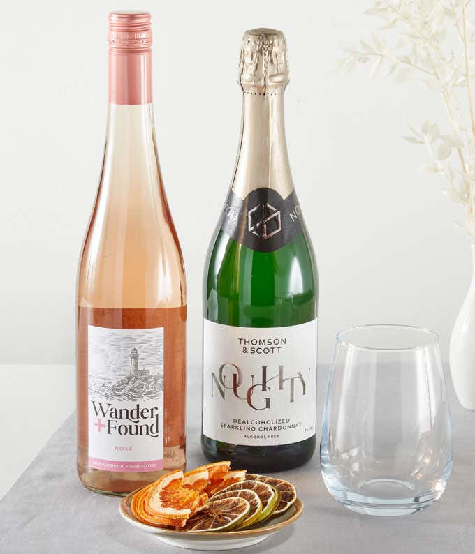 A bottle of non-alcoholic ros and a bottle of alcohol-free sparkling juice, with a glass and a plate of dried fruit slices.