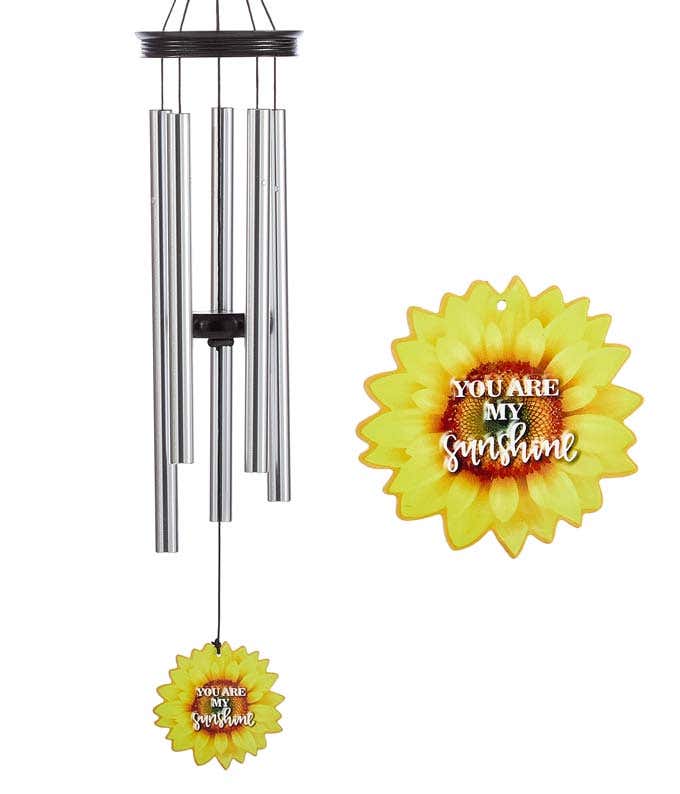 A windchime with metal rods and a wooden accents and flower shaped sail. Sail decorated as a sunflower reads you are my sunshine.