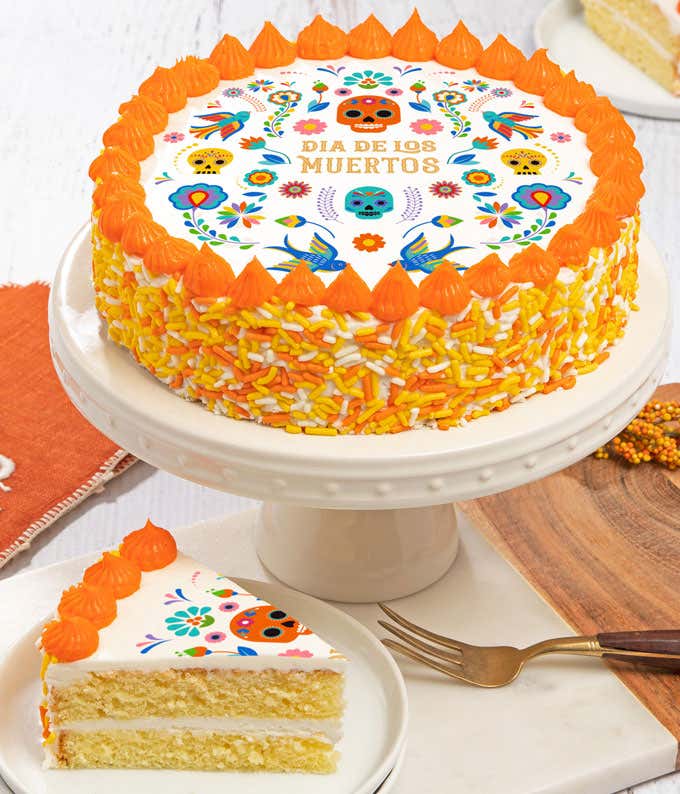 A Dia de los Muertos cake on a white stand, decorated with colorful sugar skulls, flowers, and 