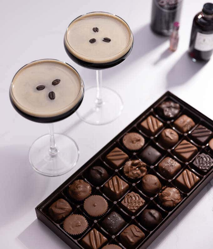 A 1 pound box of assorted milk and dark gourmet chocolates with cocktail kit that contains a 4 oz. bottle of cherry-vanilla syrup, a 3.7mL bottle of cocoa bitters, an 11oz. can of cold brew coffee, a square of dark chocolate, and a recipe card.