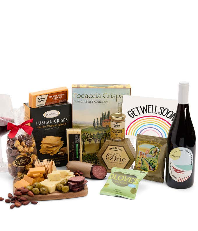 A charcuterie gift set with Tuscan crisps, focaccia crackers, 3 cheeses, summer sausage, olives, mustard, smoked almonds, chocolate-covered popcorn, a bottle of Pinot Noir, and a get well soon card.