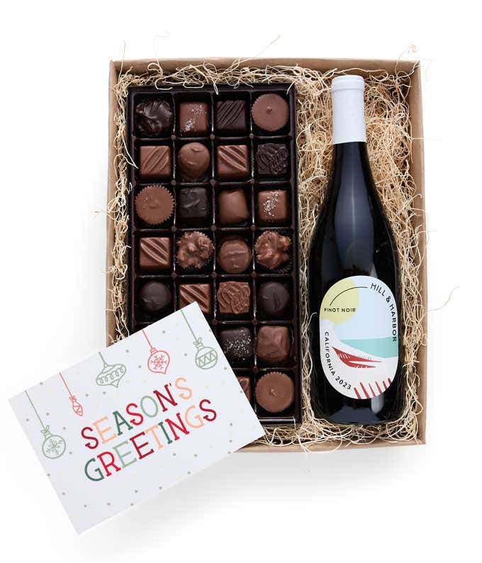 A gift box containing a bottle of California Pinot Noir, a 1 lb box of 28 assorted gourmet chocolates in a grid, and a Season's Greetings message card.   A refined combination perfect for holiday gatherings.