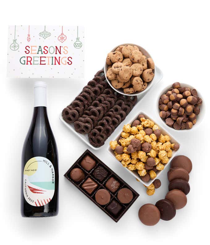 A gift set featuring a bottle of California Pinot Noir with chocolate pretzels, caramel popcorn, mini cookies, chocolate peanut butter buckeyes, chocolate-covered Oreos, assorted chocolates and a Season's Greetings card for a festive touch.