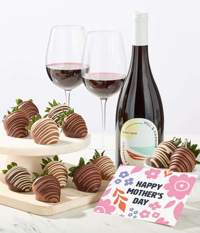 Hill & Harbor Pinot Noir bottle displayed with two glasses of red wine and assorted chocolate-covered strawberries on trays, styled with a floral Happy Mother’s Day card for an elegant dessert and wine gift.