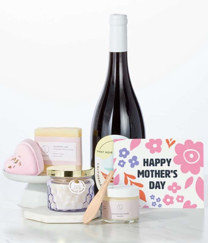 Hill & Harbor California Pinot Noir paired with spa essentials including artisan lavendar soap, a heart-shaped shower steamer, shea butter cream with wooden scoop, and a candle arranged in a clean display with a Mother's Day card.