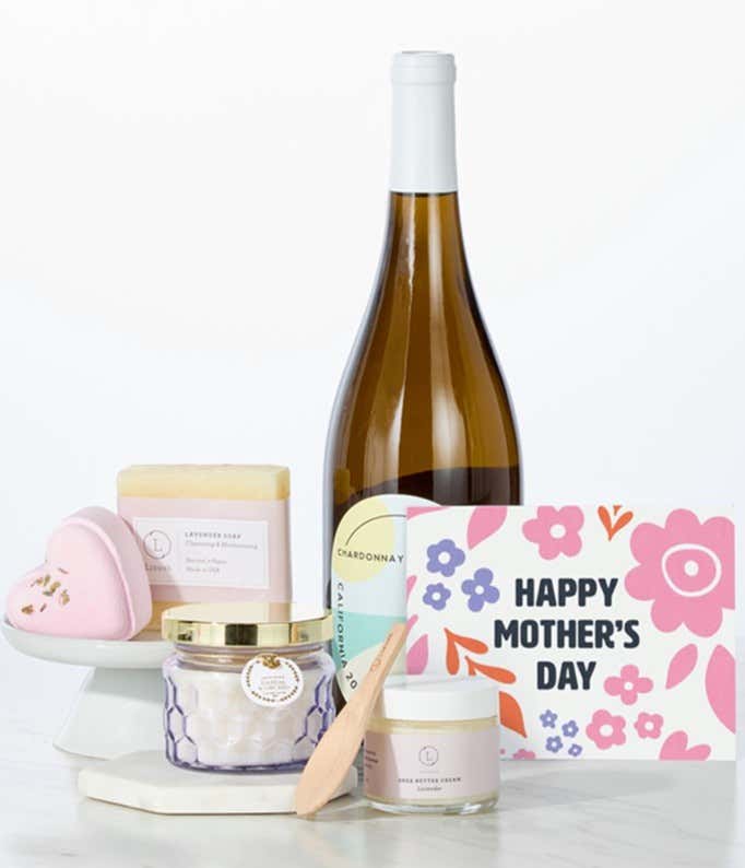 Hill & Harbor California Chardonnay paired with spa essentials including artisan lavendar soap, a heart-shaped shower steamer, shea butter cream with wooden scoop, and a candle arranged in a clean display with a Mother's Day card.