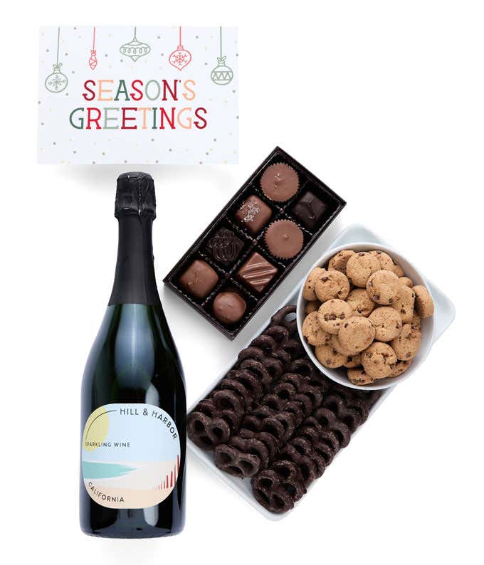 A holiday gift set with abottle of Hill & Harbor Pinot Noir, a box of assorted chocolates, a bag of chocolate-covered pretzels, a box of mini chocolate chip cookies, and a Season's Greetings message card.