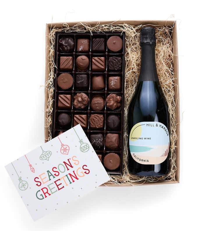 A gift box containing a bottle of California Sparkling Wine, a 1 lb box of 28 assorted gourmet chocolates in a grid, and a Season's Greetings message card.   A refined combination perfect for holiday gatherings.